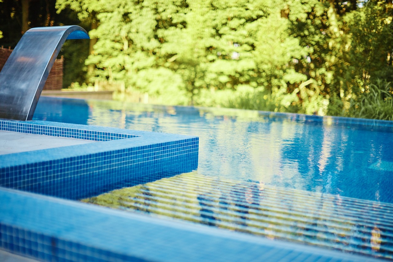 Still outdoor infinity pool by the forest.